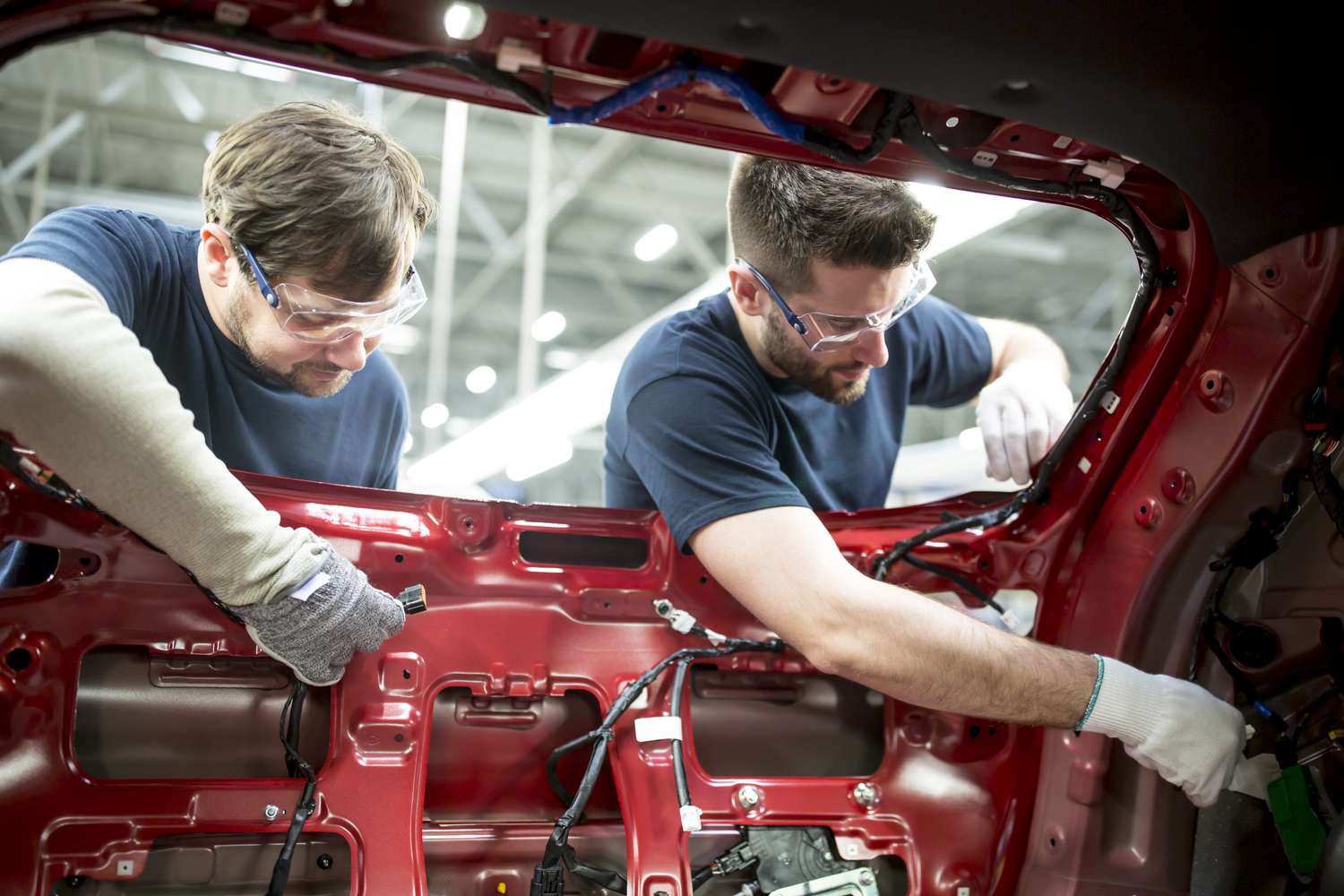 Two workers assembling a car frame