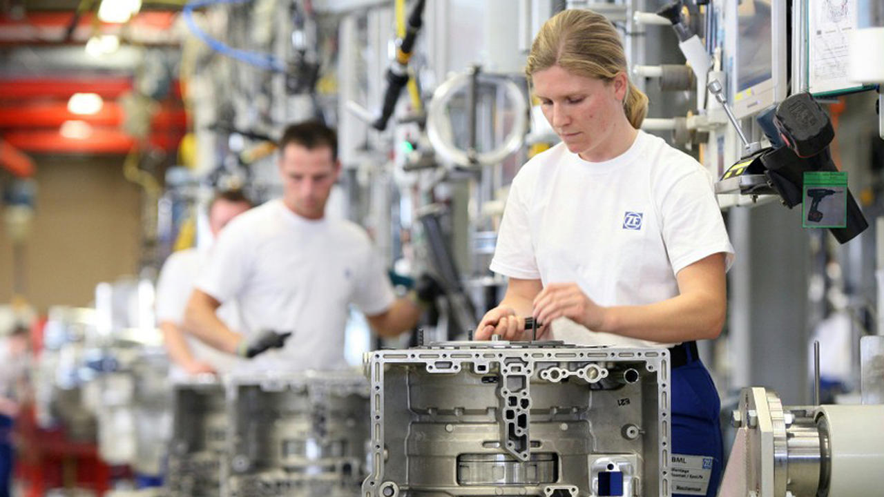 Factory worker assembling a complex metal part